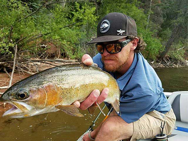 Guide Shaun Twomey holding a fish on a drift boat